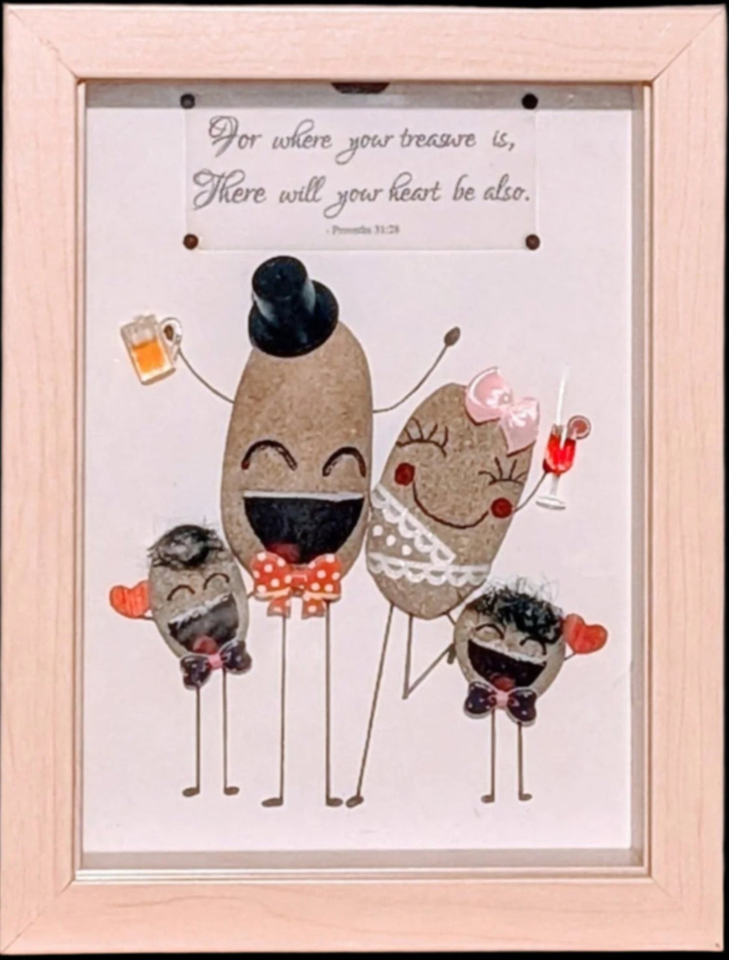 Framed pebble art of a family of four celebrating with drinks and red hearts, symbolising love, joy, and togetherness in a heartwarming family moment.