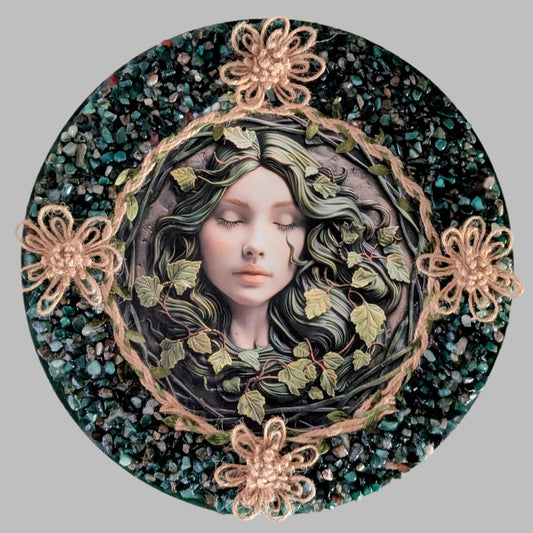 "The Sleeping Grove" is a handmade canvas featuring a print of a sleeping fairy surrounded by vines, decorated with rope flowers, and vibrant green stones.