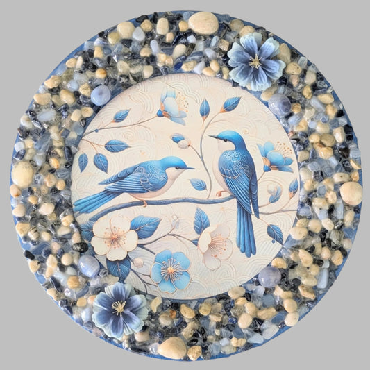 "A Pair in Bloom" is a handmade canvas featuring a print of two bluebirds on a branch, decorated with blue, cream and natural stones & pebbles and blue flowers.