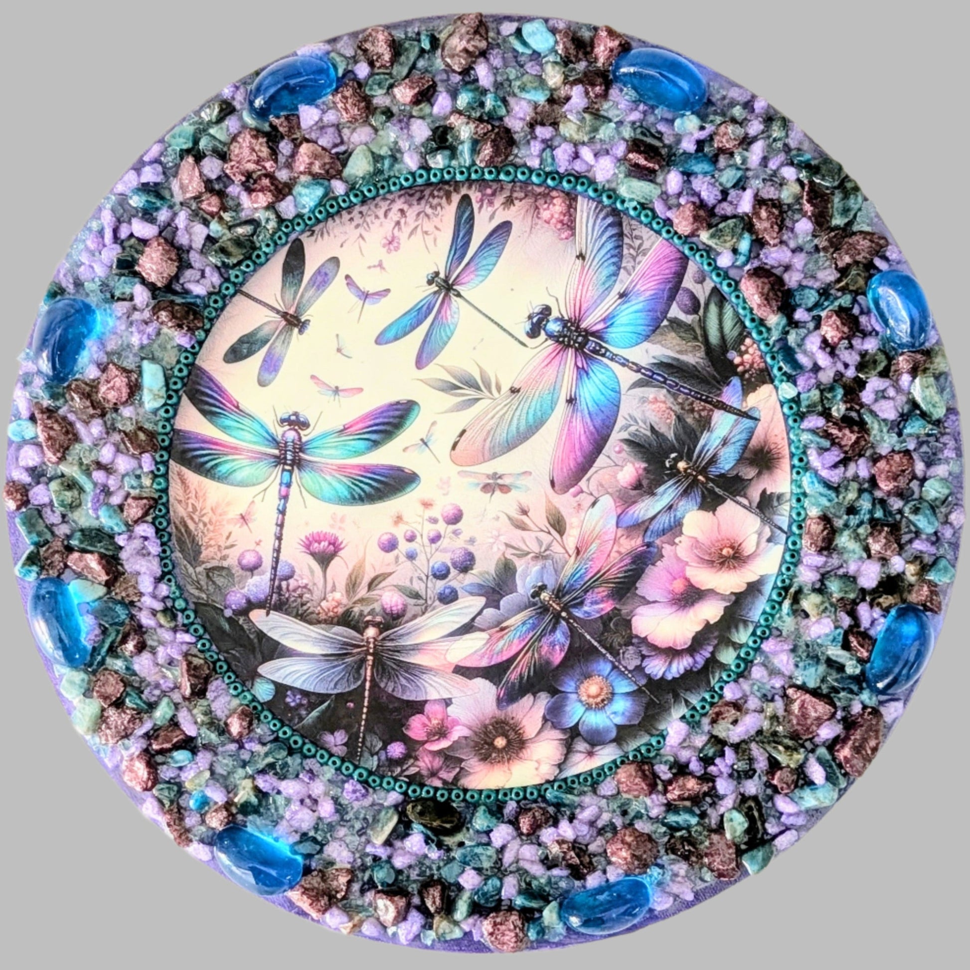 "Fluttering in Harmony" is a handmade canvas featuring a print of dragonflies decorated with green, violet, and aqua stones, creating a serene, mystical scene.