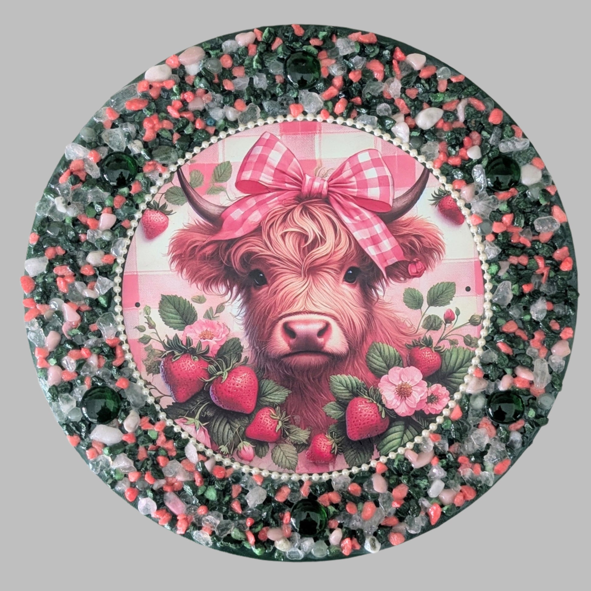 "Strawberry Fields and Tartan Bows" is a handmade canvas featuring a print of a cow with a red tartan bow, surrounded by strawberries and decorated with green stones and green, red, pink & clear stones & pebbles.