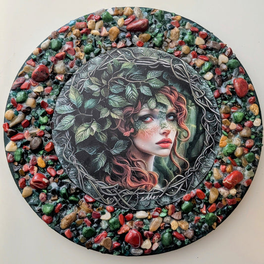 "Veil of Vines" is a handmade canvas featuring a print of a fairy amidst lush vines, decorated with earthy stones creating depth and enchantment.