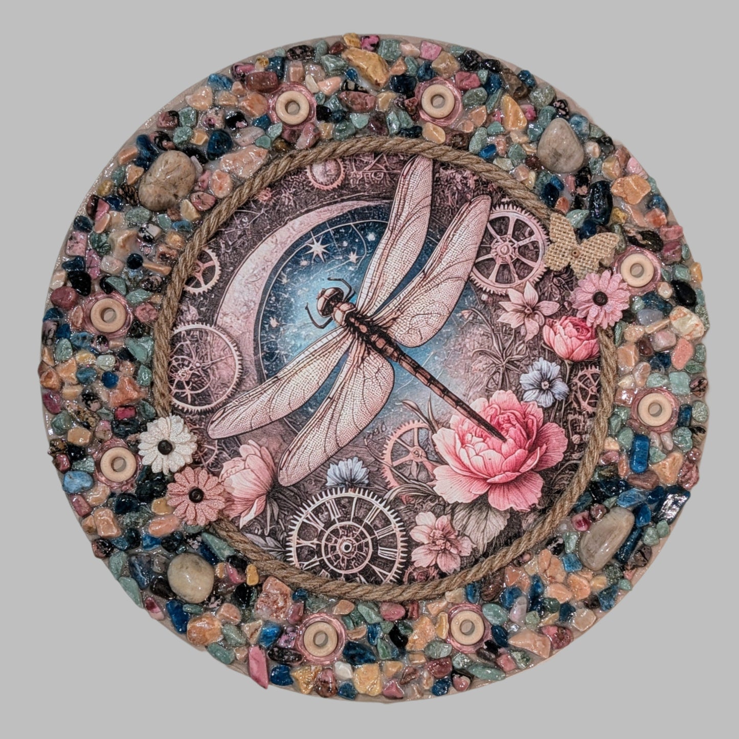 Handmade canvas with a dragonfly, flowers, old-fashioned clocks, pebbles, stones, rope, wooden rings, faux flowers, and a rattan butterfly.