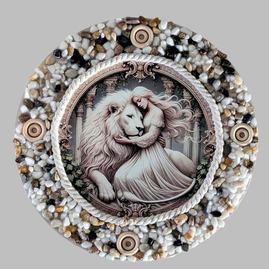 "The Lioness Touch" is a handmade canvas featuring a print of a white lion and lady in a tender embrace, framed by earthy stones and wooden accents.